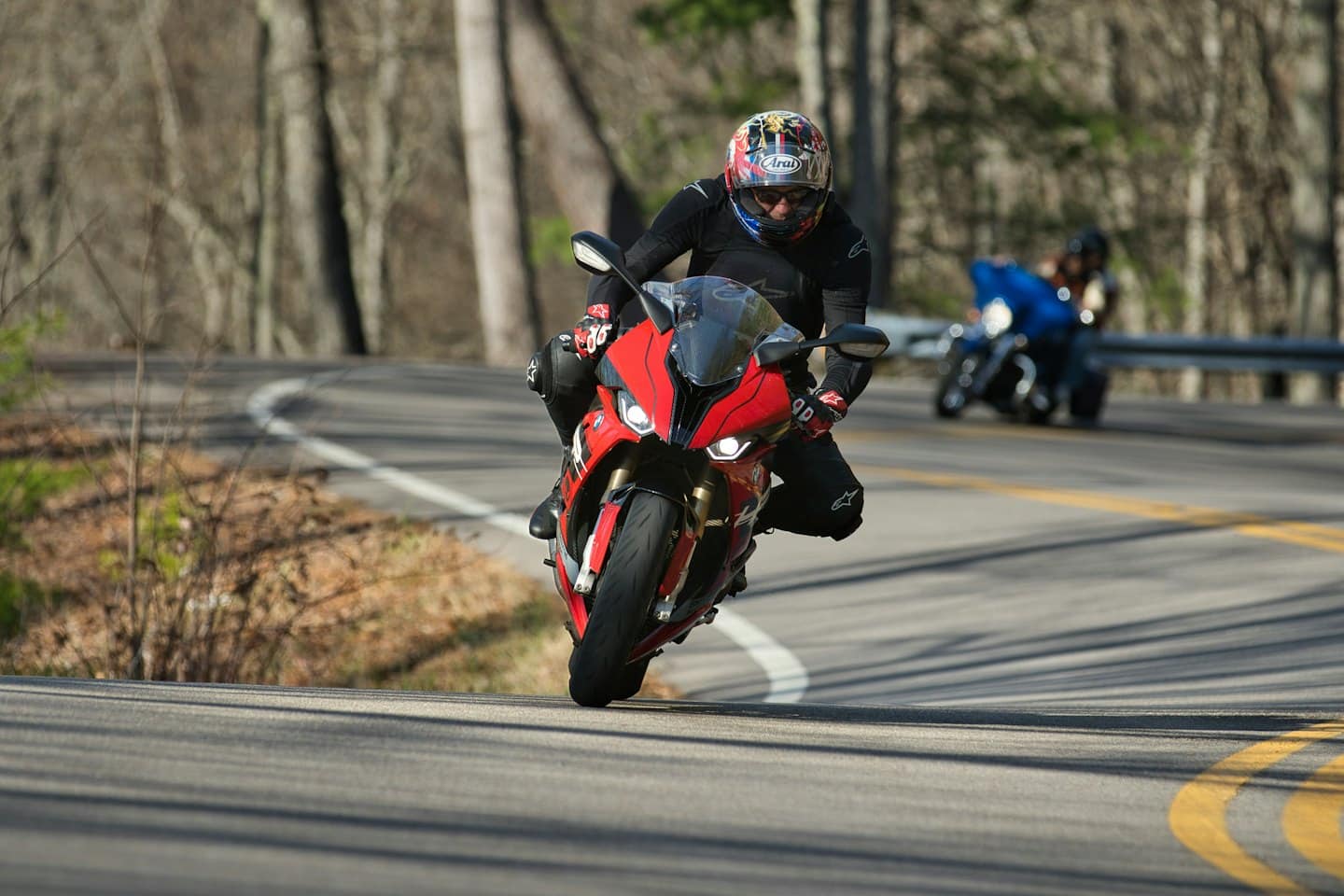 Motocyklista na czerwonym motocyklu sportowym skręca na krętej drodze.