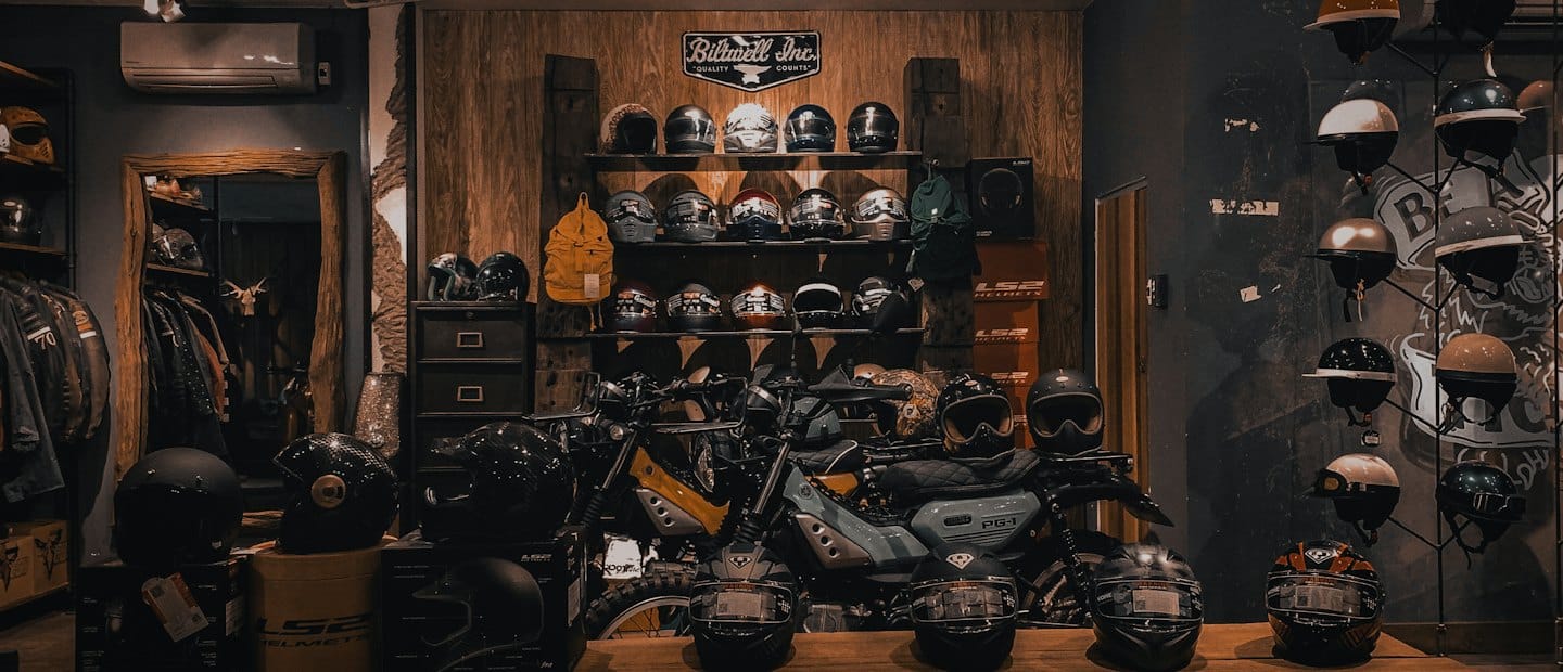 Kaski motocyklowe i motocykle wystawione w sklepie z odzieżą w stylu vintage.