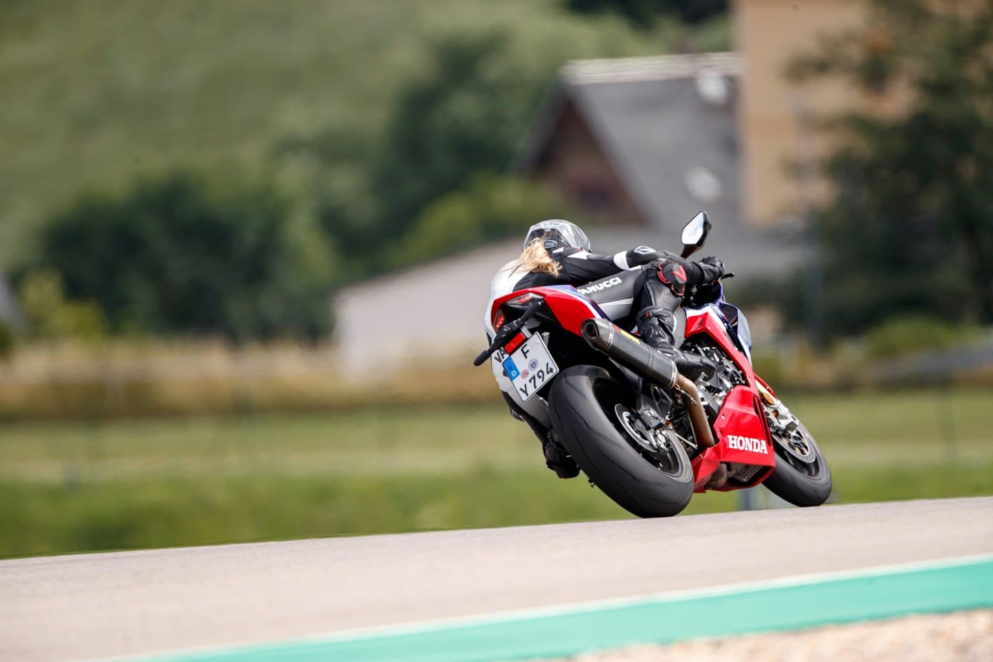 Motocyklista pochyla się w zakręcie na torze wyścigowym.