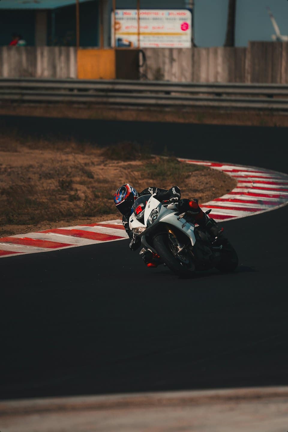 Motocyklista w stroju wyścigowym pochylony na zakręcie toru.