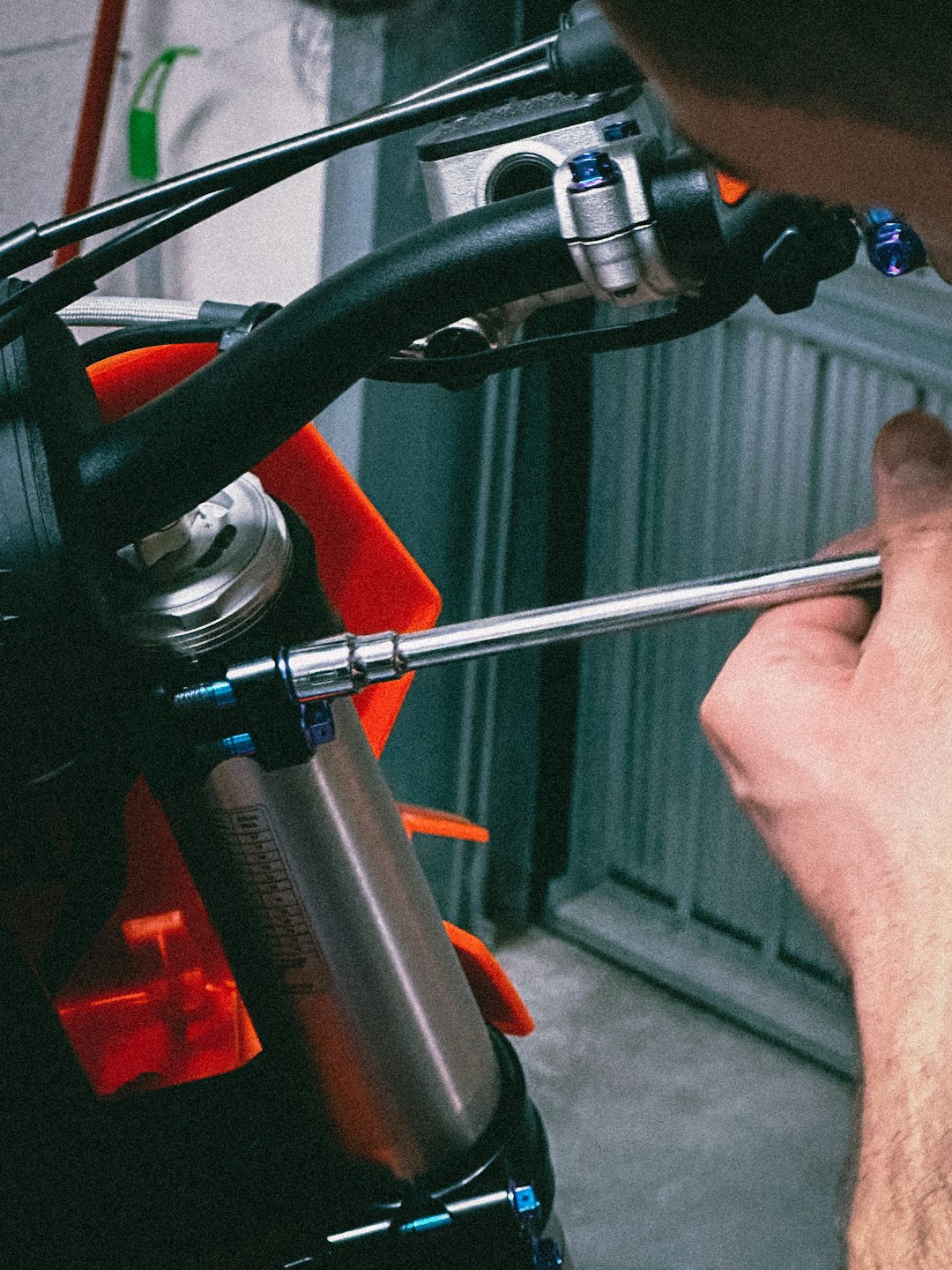 Mechanik reguluje śrubę zawieszenia motocykla kluczem.