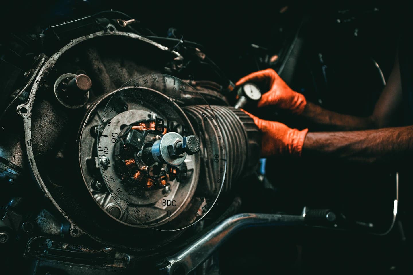 Ręce mechanika w rękawiczkach pracujące nad silnikiem motocykla.